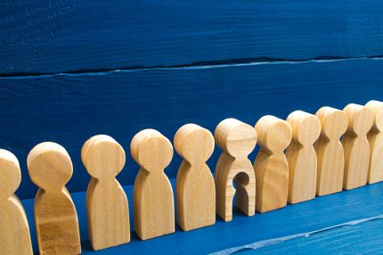 Holzfiguren in einer Reihe, eine hat ein ausgeschnittenes Kind